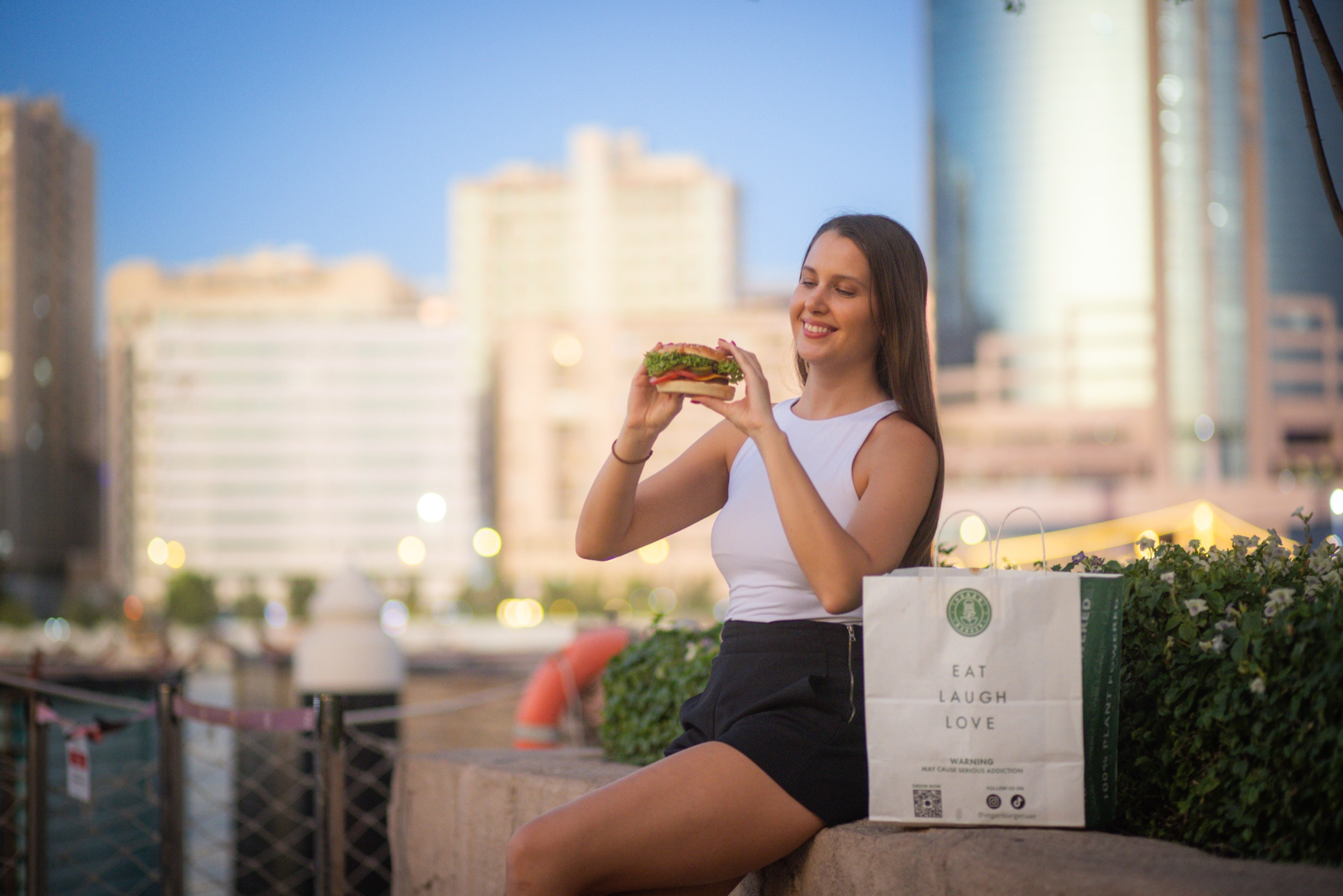 Woman enjoying burger with city background